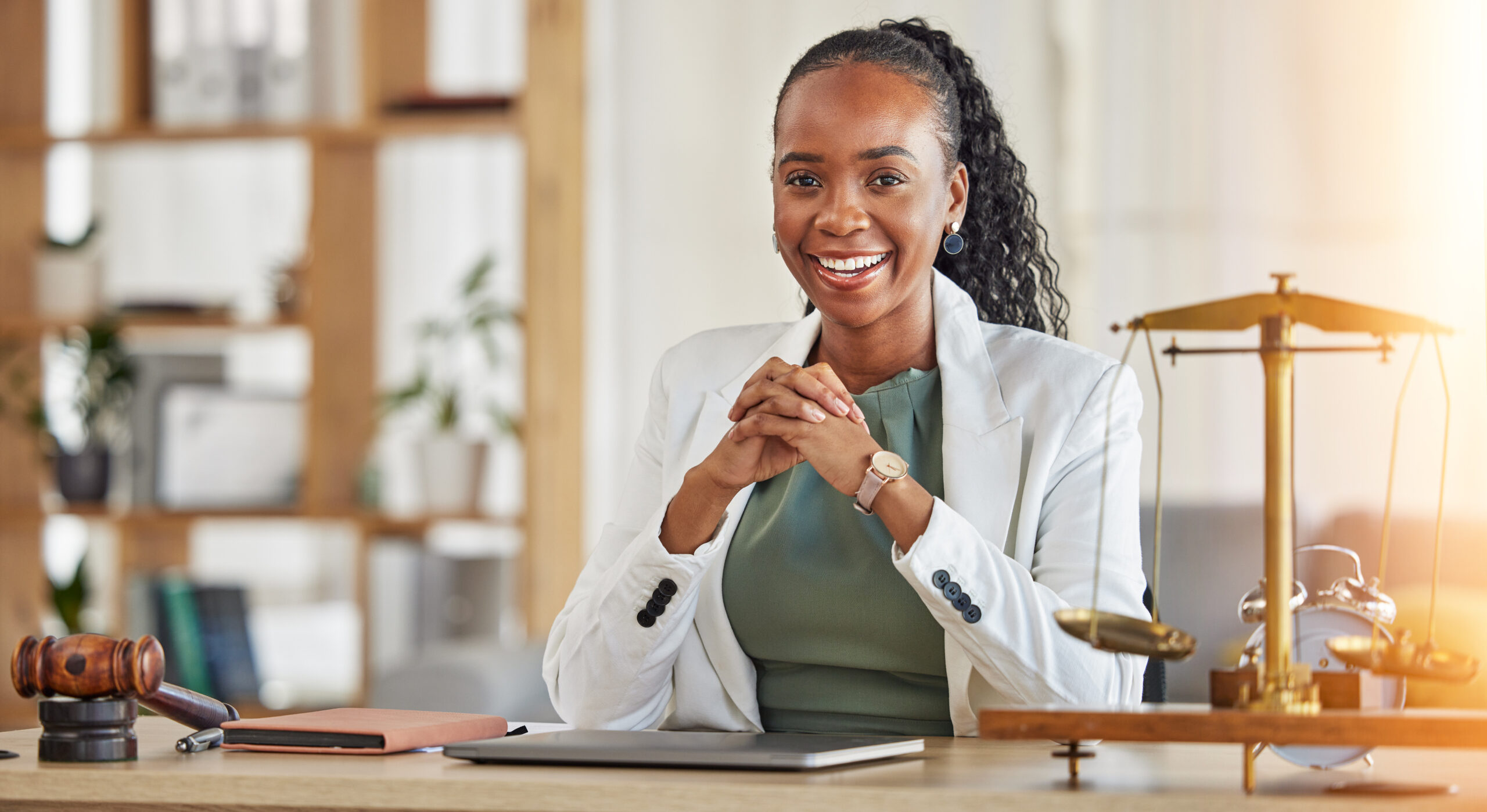 A smiling woman in a business suit sitting at a desk.