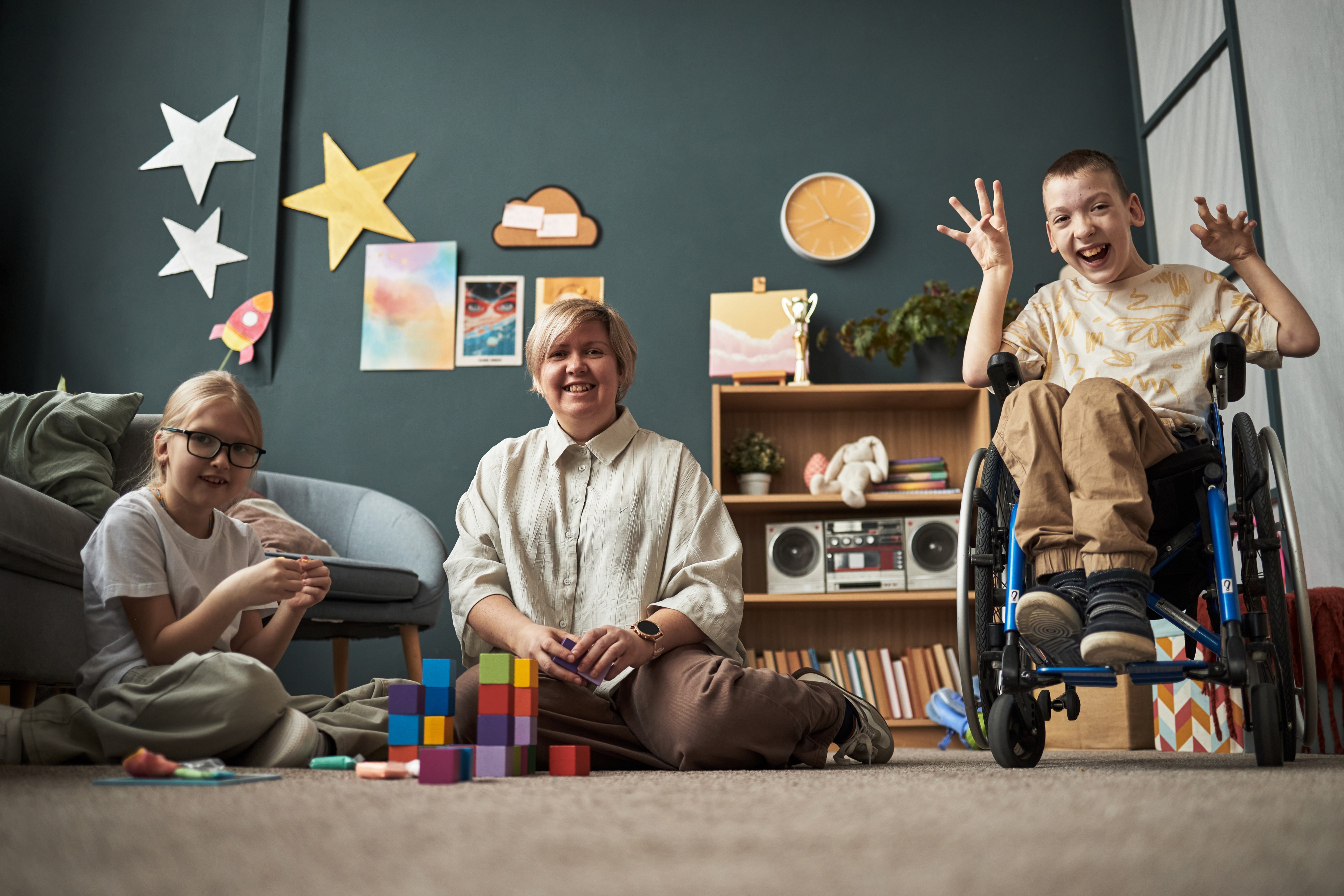 Boy in wheelchair playing blocks with woman and girl