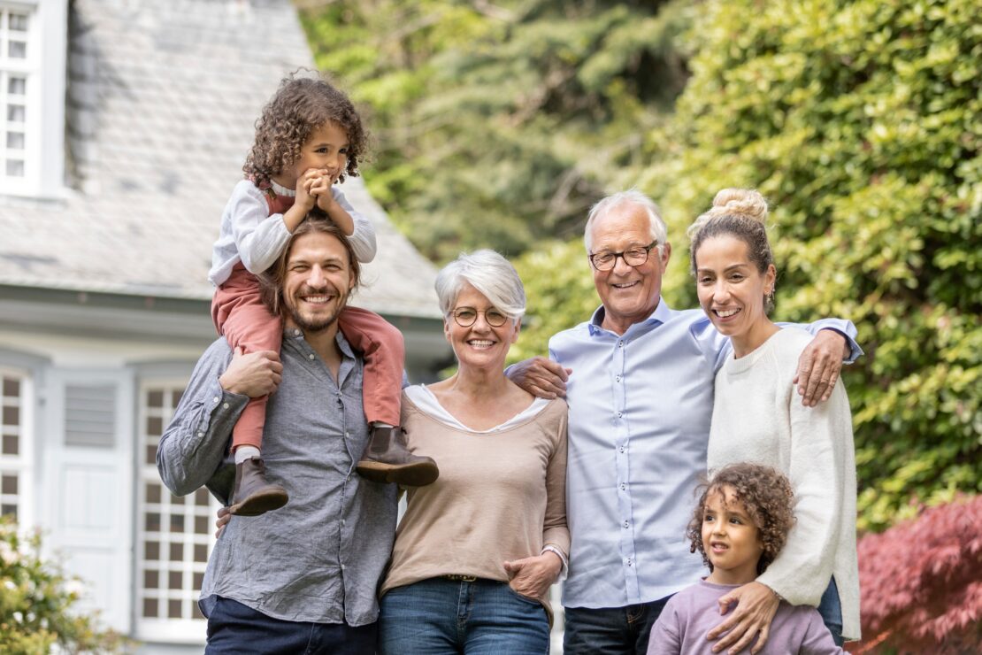 Multigenerational family smiling outside home