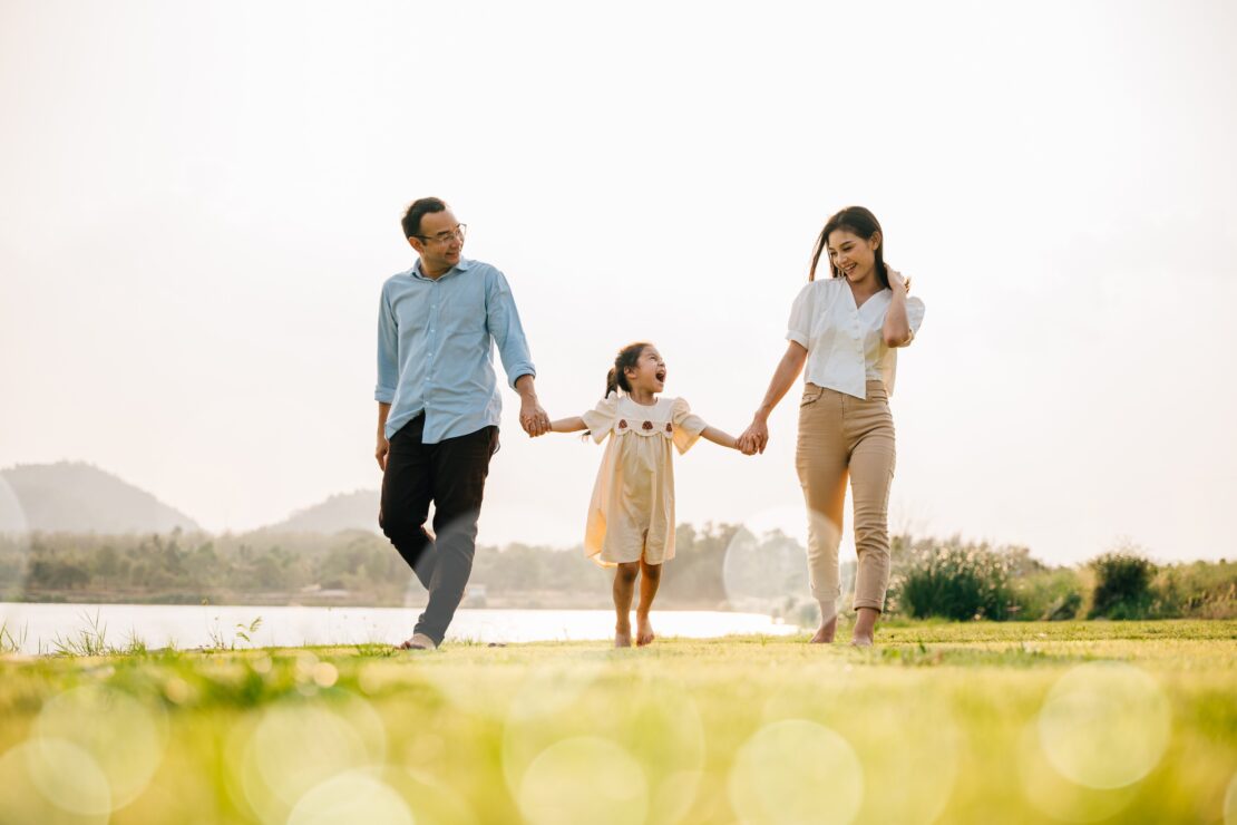 Family walking barefoot on grass near lake