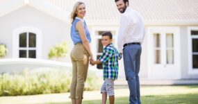 Family holding hands outside new house