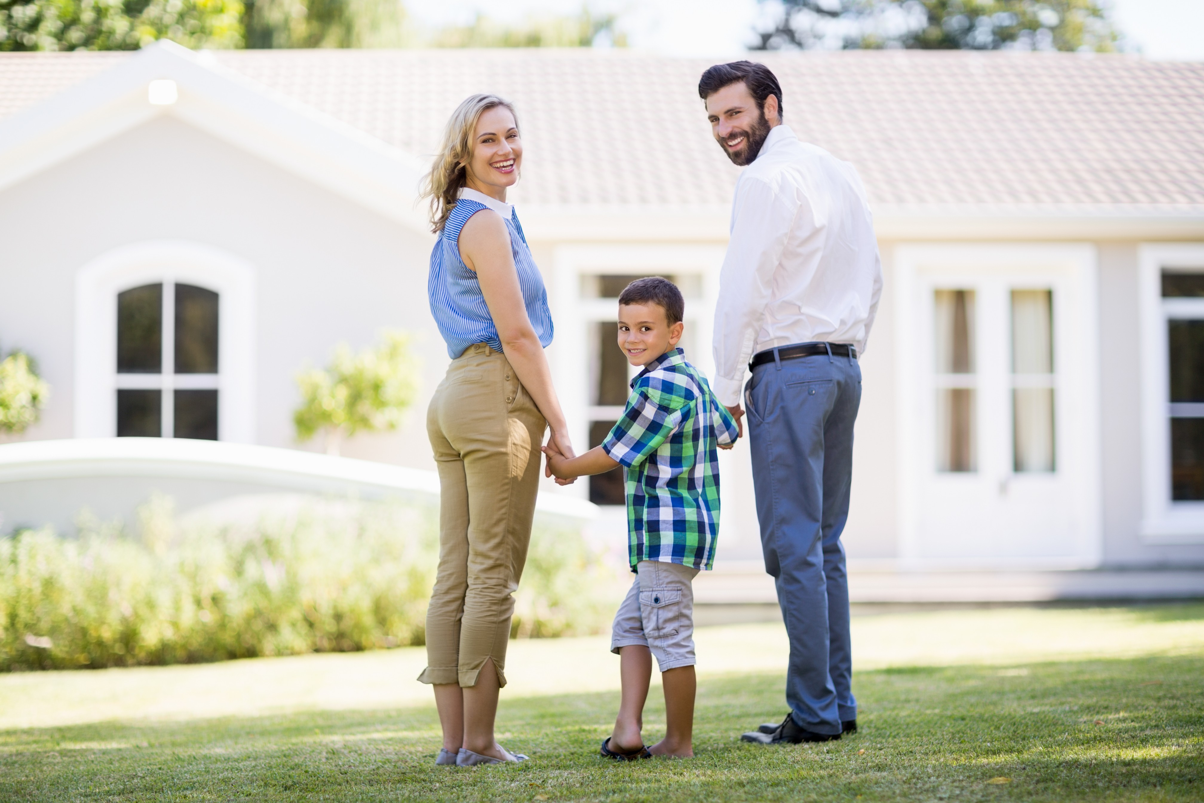 Family holding hands outside new house