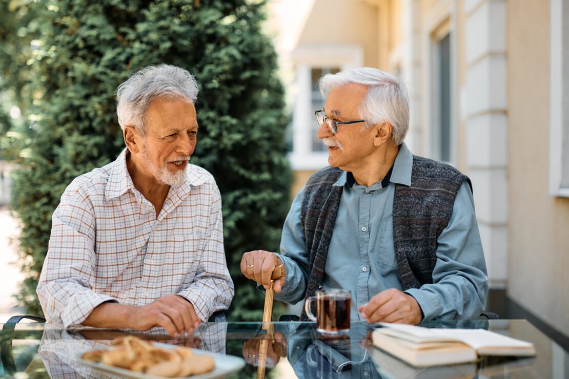 Elderly men talking outdoors with coffee