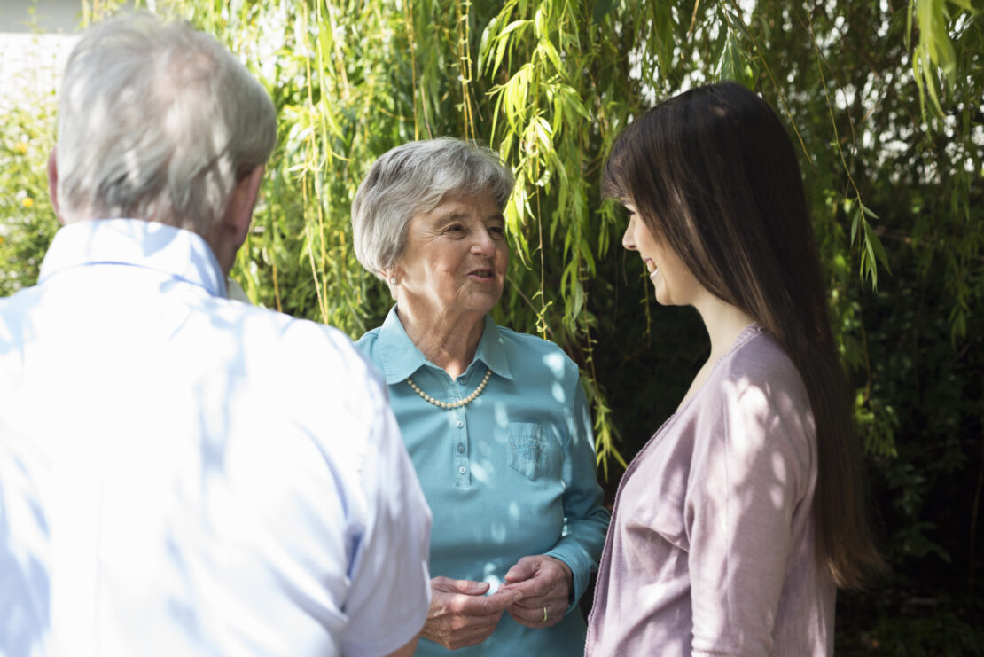 Elderly woman talking with younger people outdoors